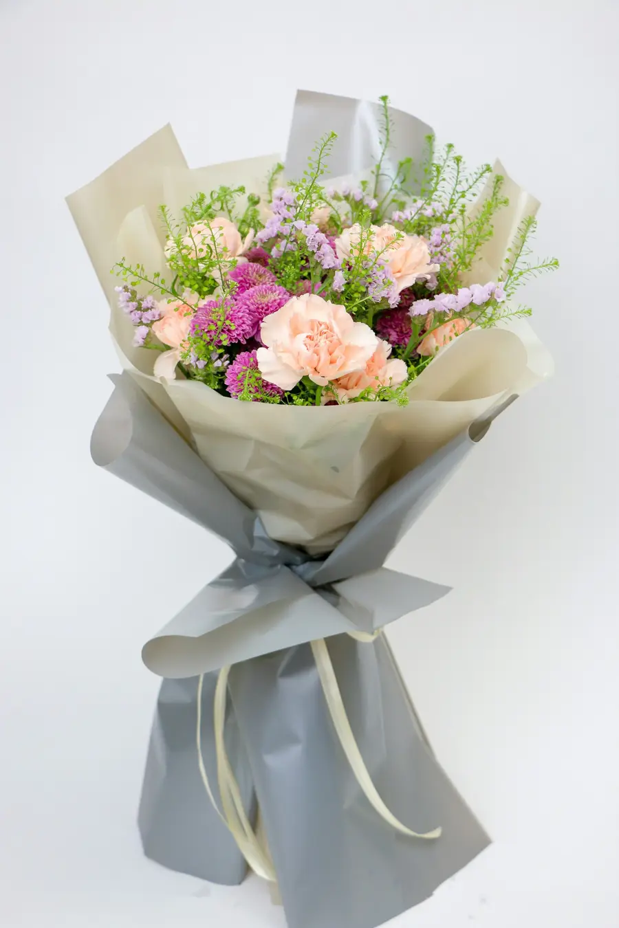 Pastelkleurig boeket met anjers en lathyrus in grijs papier